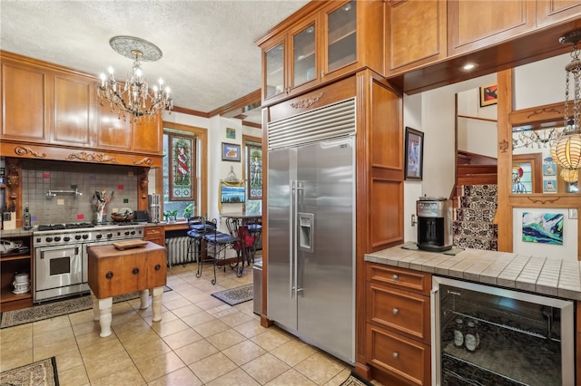 kitchen featuring beverage cooler, decorative light fixtures, a textured ceiling, high quality appliances, and tile countertops