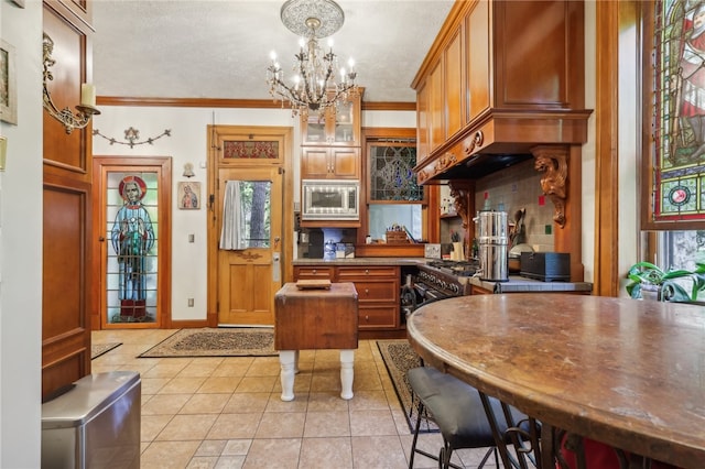 kitchen featuring stainless steel microwave, light tile floors, hanging light fixtures, ornamental molding, and a chandelier