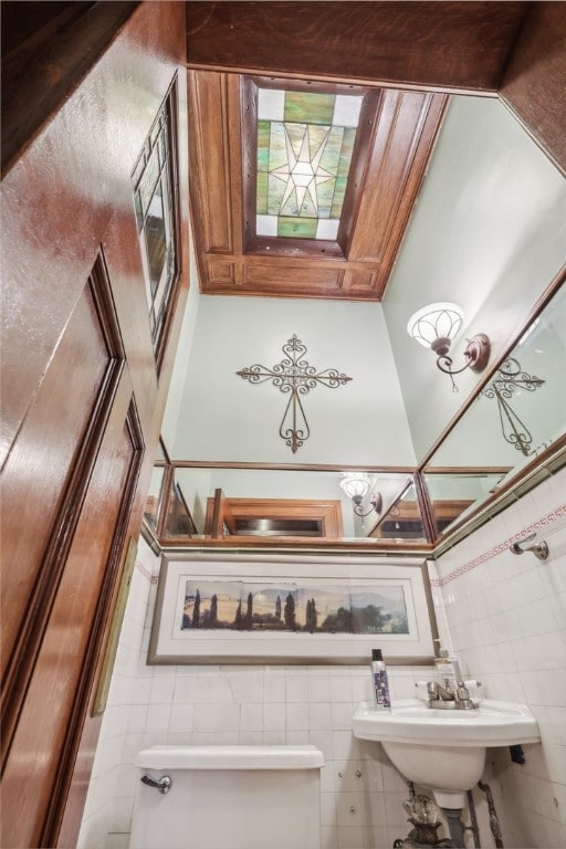 bathroom featuring toilet and tile walls