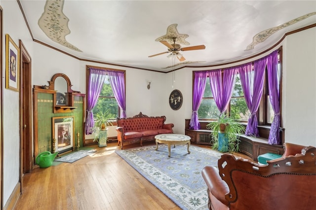 living room featuring ornamental molding, wood-type flooring, and ceiling fan