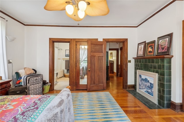 bedroom with ceiling fan, a fireplace, wood-type flooring, ornamental molding, and connected bathroom