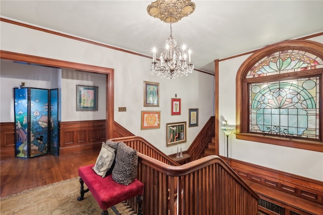 hall with ornamental molding, hardwood / wood-style flooring, and a chandelier