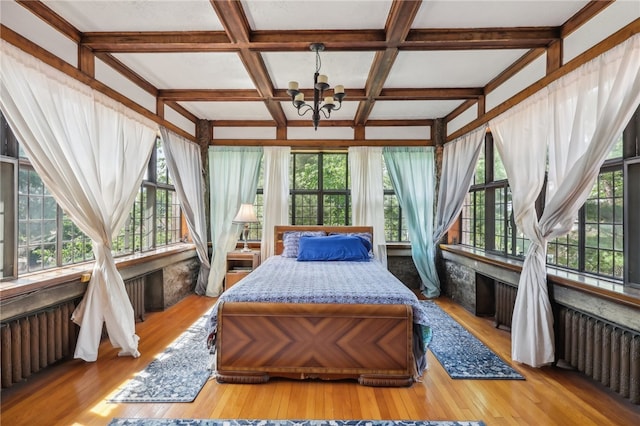 bedroom with coffered ceiling, multiple windows, and light hardwood / wood-style flooring