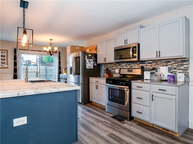 kitchen featuring white cabinets, hanging light fixtures, hardwood / wood-style flooring, sink, and stainless steel appliances