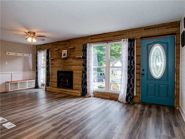 entrance foyer with ceiling fan, dark hardwood / wood-style floors, and wood walls