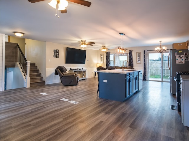 kitchen with sink, dark hardwood / wood-style flooring, hanging light fixtures, a breakfast bar, and a kitchen island with sink