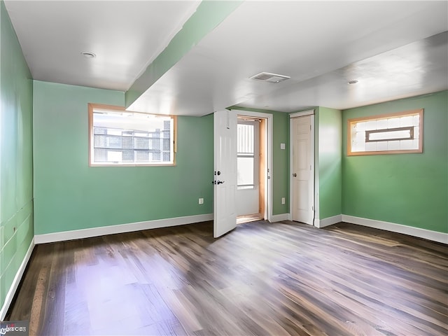 empty room with dark hardwood / wood-style floors and a wealth of natural light