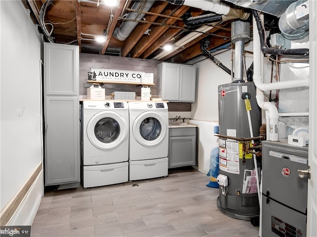 laundry room with cabinets, separate washer and dryer, light wood-type flooring, water heater, and sink