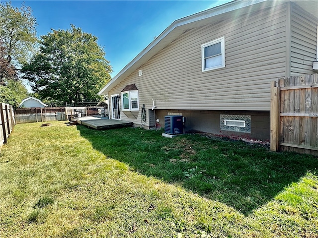 rear view of house with central AC, a yard, and a wooden deck