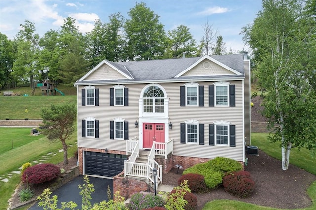 view of front of home featuring a garage, cooling unit, a front yard, and a playground