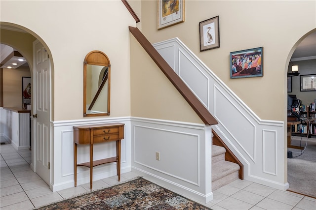 stairs featuring ornamental molding and light tile flooring