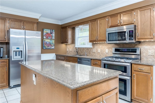 kitchen with light stone countertops, light tile flooring, a kitchen island, sink, and appliances with stainless steel finishes