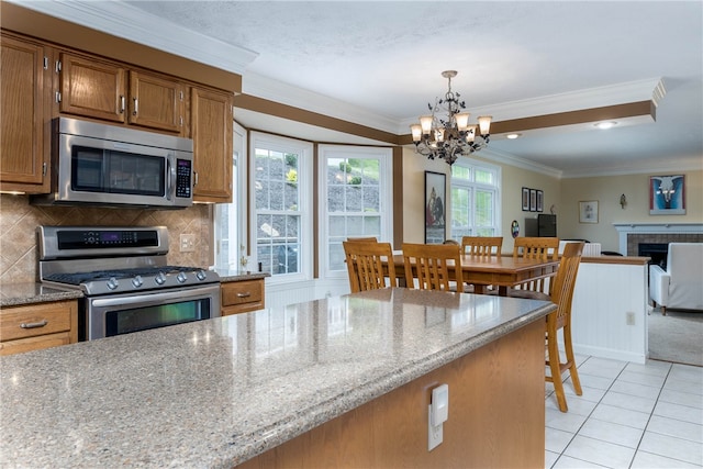 kitchen featuring stainless steel appliances, a chandelier, tasteful backsplash, and a tile fireplace