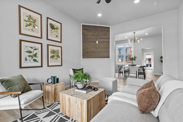 living room with ceiling fan with notable chandelier and light hardwood / wood-style flooring