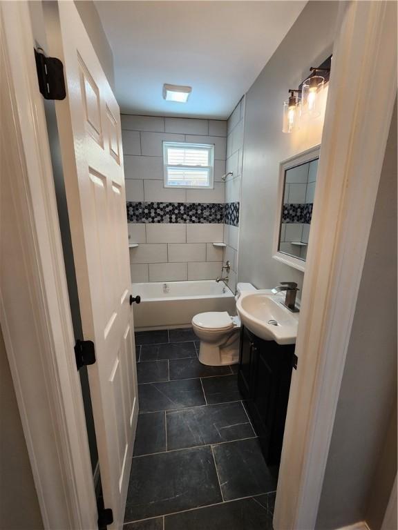 full bathroom featuring tiled shower / bath, vanity, and toilet