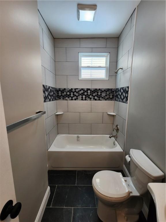 bathroom with tiled shower / bath, tile patterned floors, and toilet