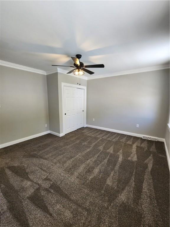 unfurnished bedroom featuring ornamental molding, carpet, ceiling fan, and a closet