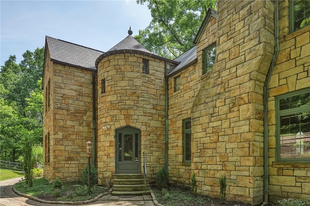 exterior space featuring stone siding and a high end roof