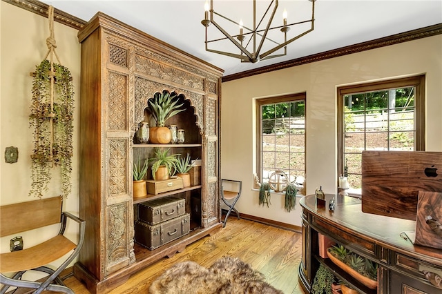 office area with a healthy amount of sunlight, ornamental molding, wood-type flooring, and an inviting chandelier