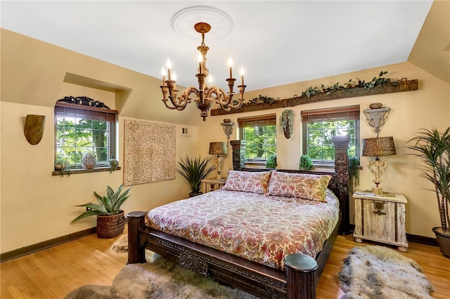 bedroom featuring vaulted ceiling, a chandelier, hardwood / wood-style flooring, and multiple windows