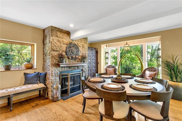 dining room featuring a stone fireplace and light wood-type flooring