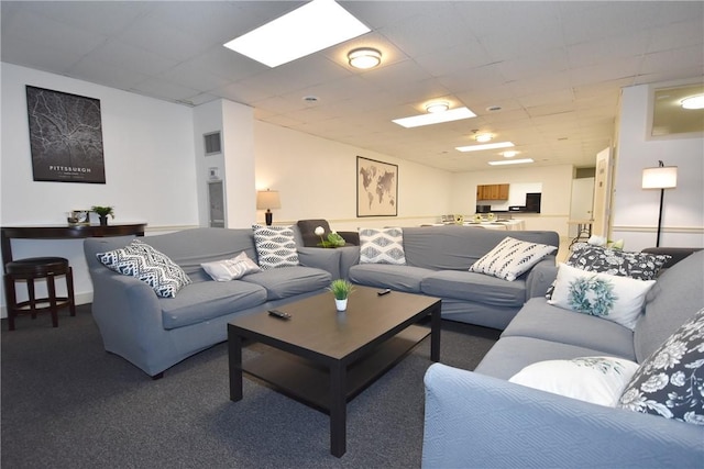 living room featuring a paneled ceiling and carpet