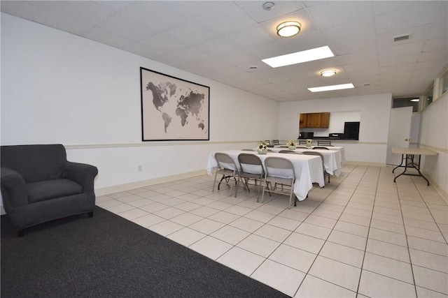 dining area with light tile patterned flooring and a drop ceiling