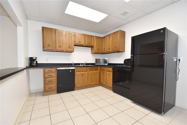 kitchen featuring black appliances, a paneled ceiling, light tile patterned flooring, and sink