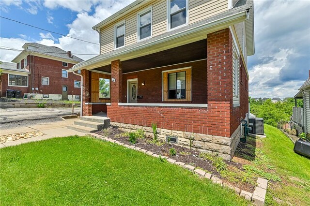 view of front of house featuring a front yard, a porch, and central AC