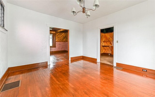 spare room with a notable chandelier and hardwood / wood-style flooring