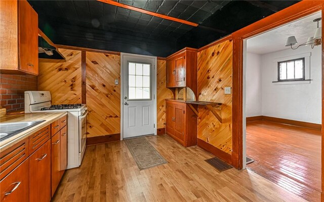 kitchen with range hood, white range with gas cooktop, and light hardwood / wood-style flooring