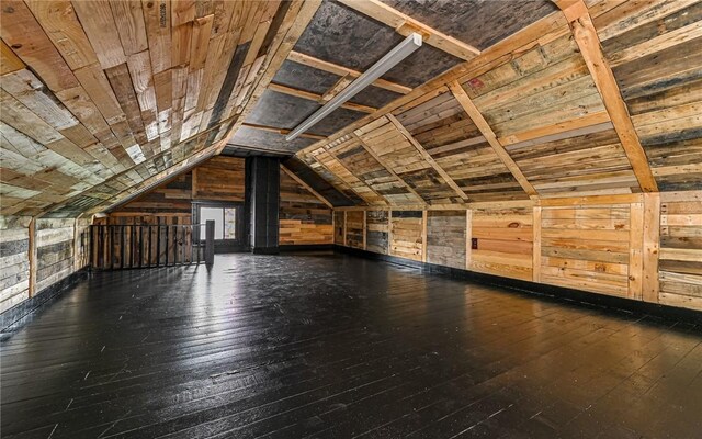 additional living space with wooden walls, dark hardwood / wood-style flooring, and vaulted ceiling