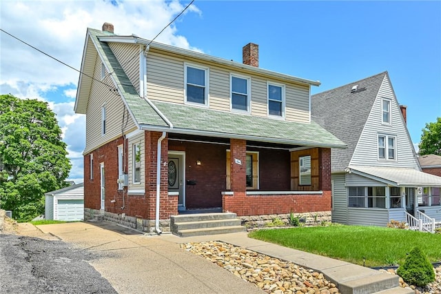 view of front of home featuring a garage, an outdoor structure, a front lawn, and covered porch