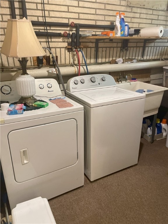 clothes washing area featuring washing machine and dryer and brick wall