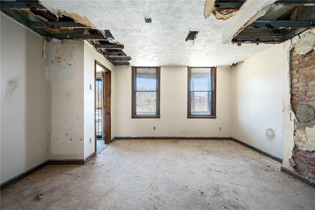 empty room with a textured ceiling and brick wall