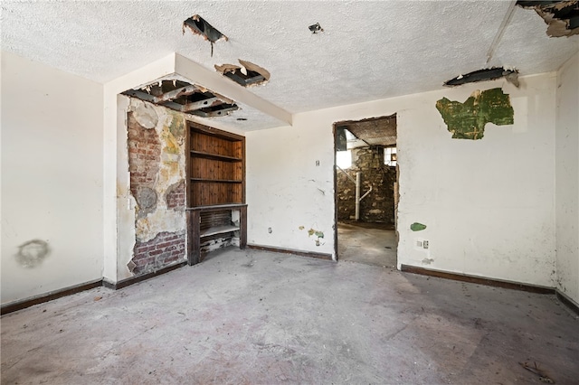 spare room featuring brick wall, a textured ceiling, and concrete flooring