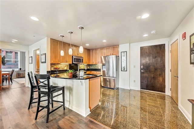 kitchen featuring tasteful backsplash, stainless steel appliances, decorative light fixtures, wood-type flooring, and sink