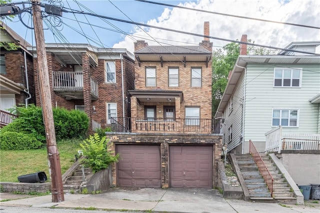 multi unit property featuring brick siding, stairway, concrete driveway, and a garage