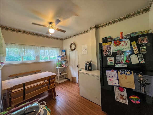 bedroom with wood-type flooring, ceiling fan, and black refrigerator