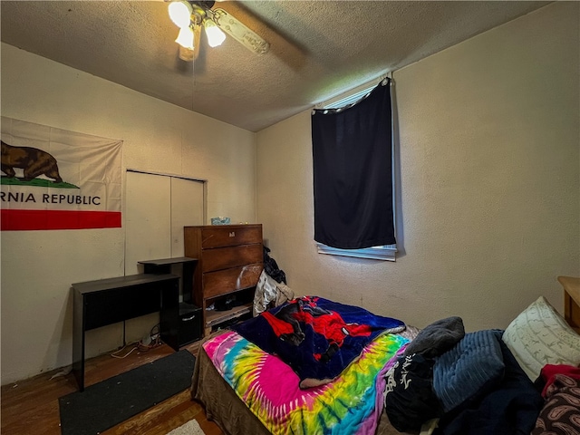 bedroom with wood-type flooring, a closet, ceiling fan, and a textured ceiling