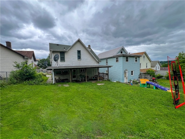 rear view of property with a yard and a playground