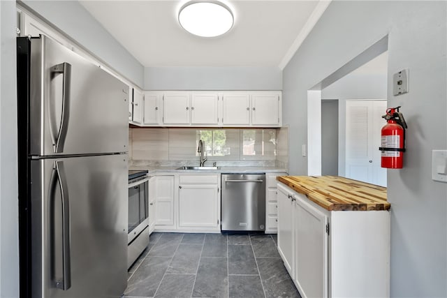 kitchen with sink, appliances with stainless steel finishes, white cabinets, and backsplash