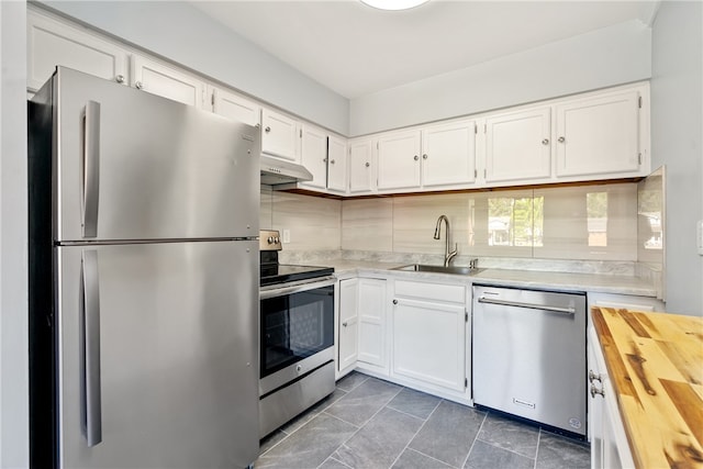 kitchen with backsplash, white cabinets, sink, appliances with stainless steel finishes, and dark tile patterned flooring