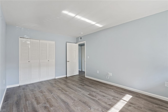 unfurnished bedroom featuring wood-type flooring and a closet