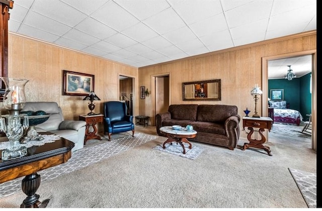 living room featuring a notable chandelier, wooden walls, and carpet