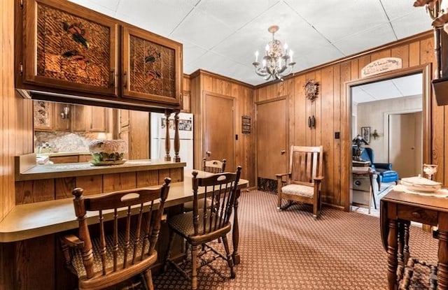 carpeted dining area featuring a chandelier and a paneled ceiling