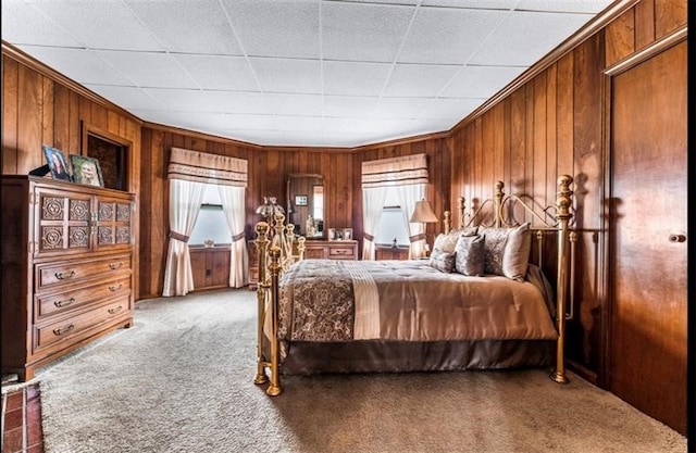 carpeted bedroom featuring wood walls and crown molding