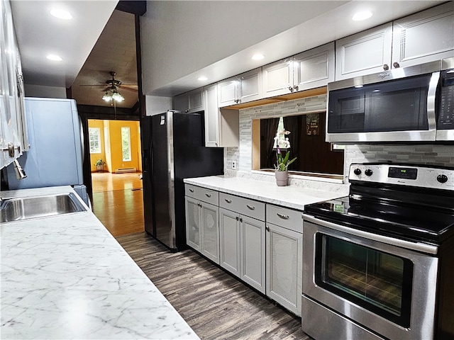 kitchen featuring dark hardwood / wood-style flooring, tasteful backsplash, ceiling fan, and stainless steel appliances