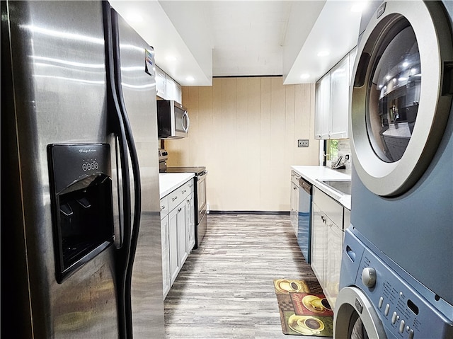 laundry room with stacked washer / drying machine and light hardwood / wood-style flooring