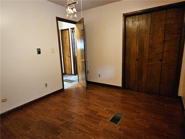 unfurnished bedroom with a closet and dark hardwood / wood-style flooring